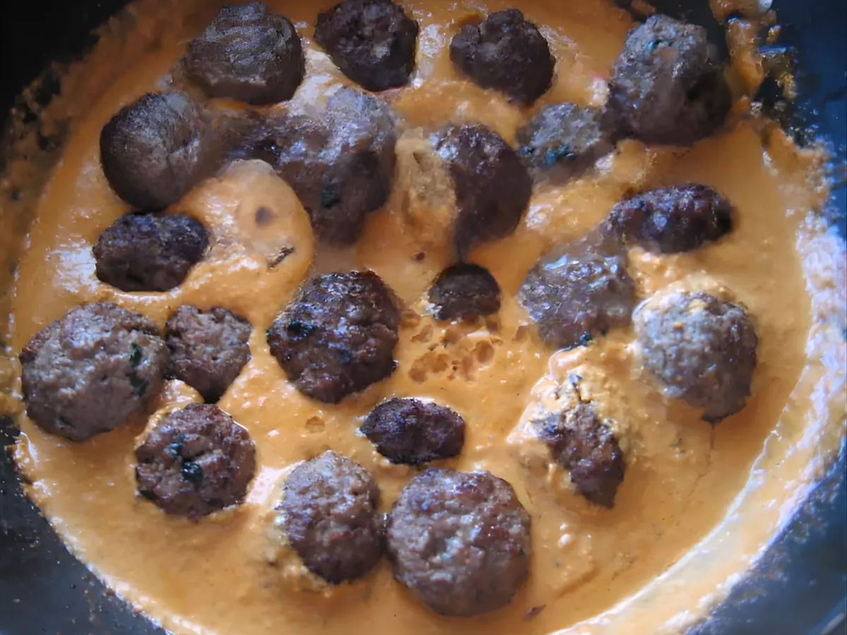 Lamb kofta meatballs simmering in a creamy curry sauce.