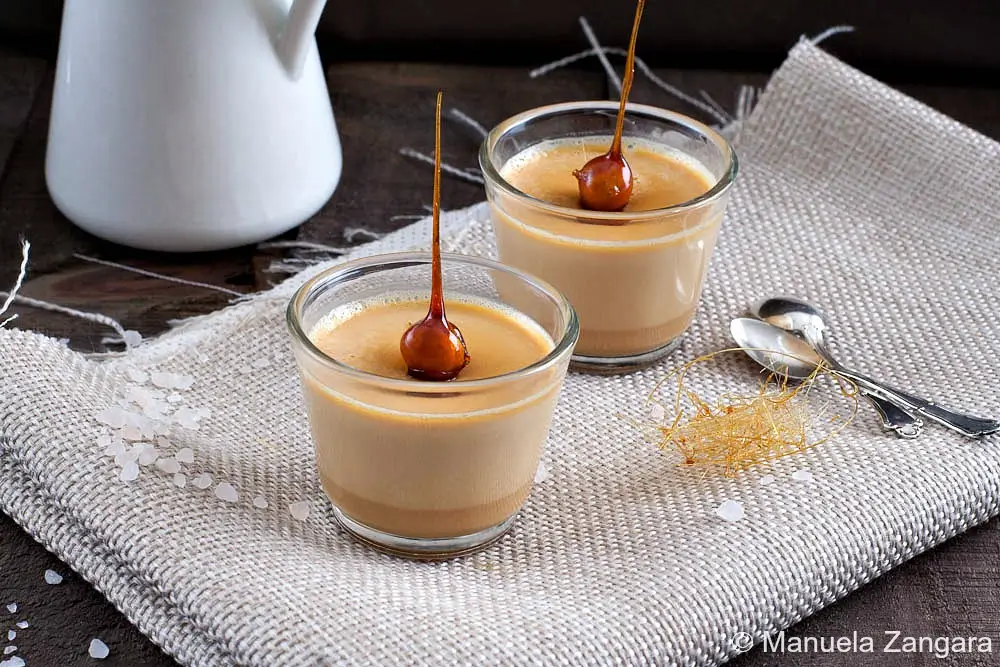Close-up of caramel panna cotta with a caramel-dipped hazelnut on top.