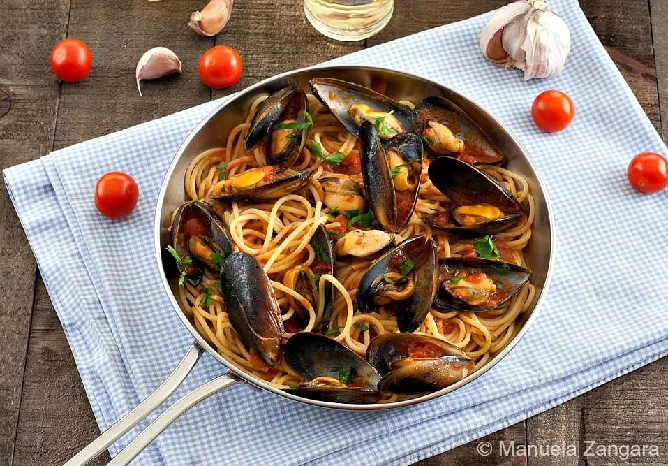 Spaghetti with Mussels in tomato and white wine sauce, garnished with parsley and cherry tomatoes.