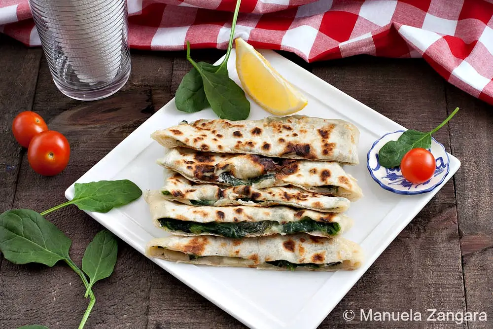 Pan-cooked spinach and feta gozleme served on a white plate.