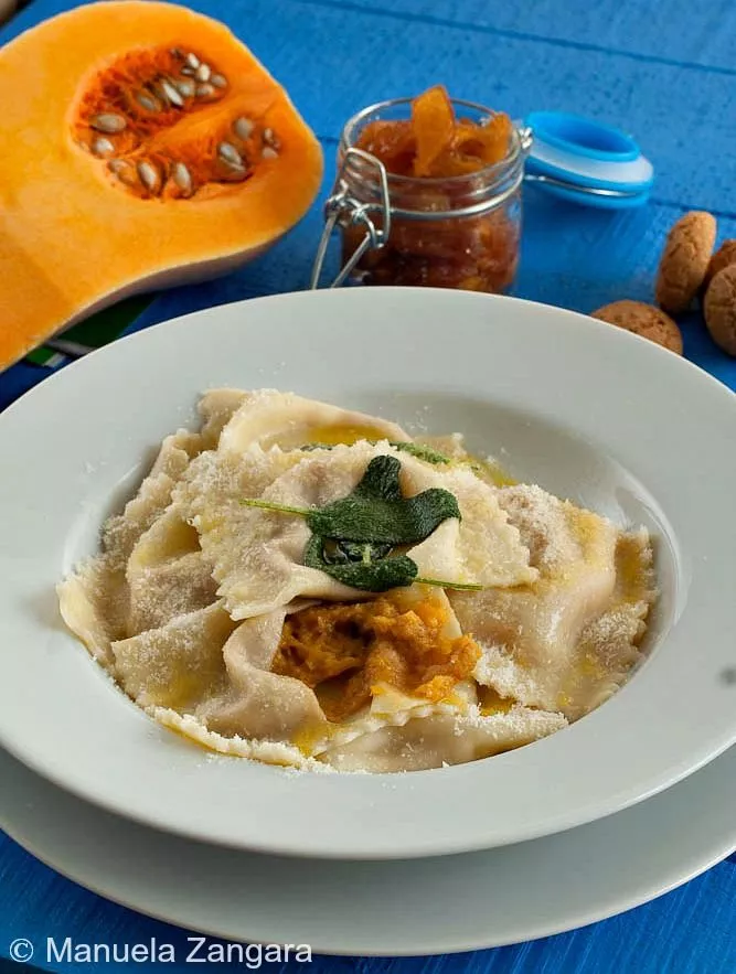 A plate of Tortelli di Zucca topped with butter, sage, and Parmigiano Reggiano.