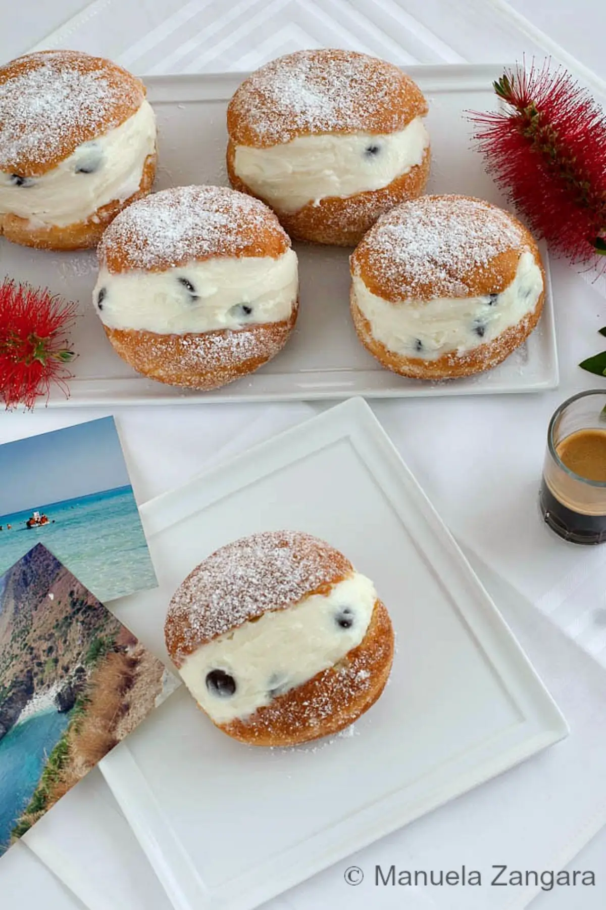 Ricotta Graffe dusted with icing sugar and filled with sweet ricotta cream on a white platter.
