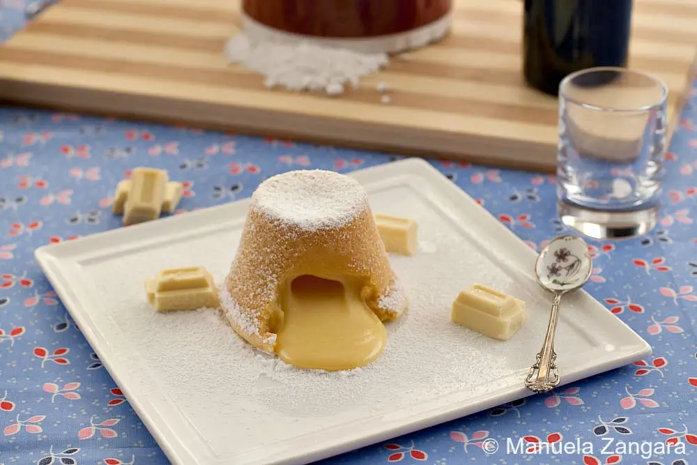 Individual white chocolate pudding served warm on a plate, dusted with icing sugar.