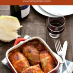 Baked cabbage rolls in tomato sauce served in a red baking dish.