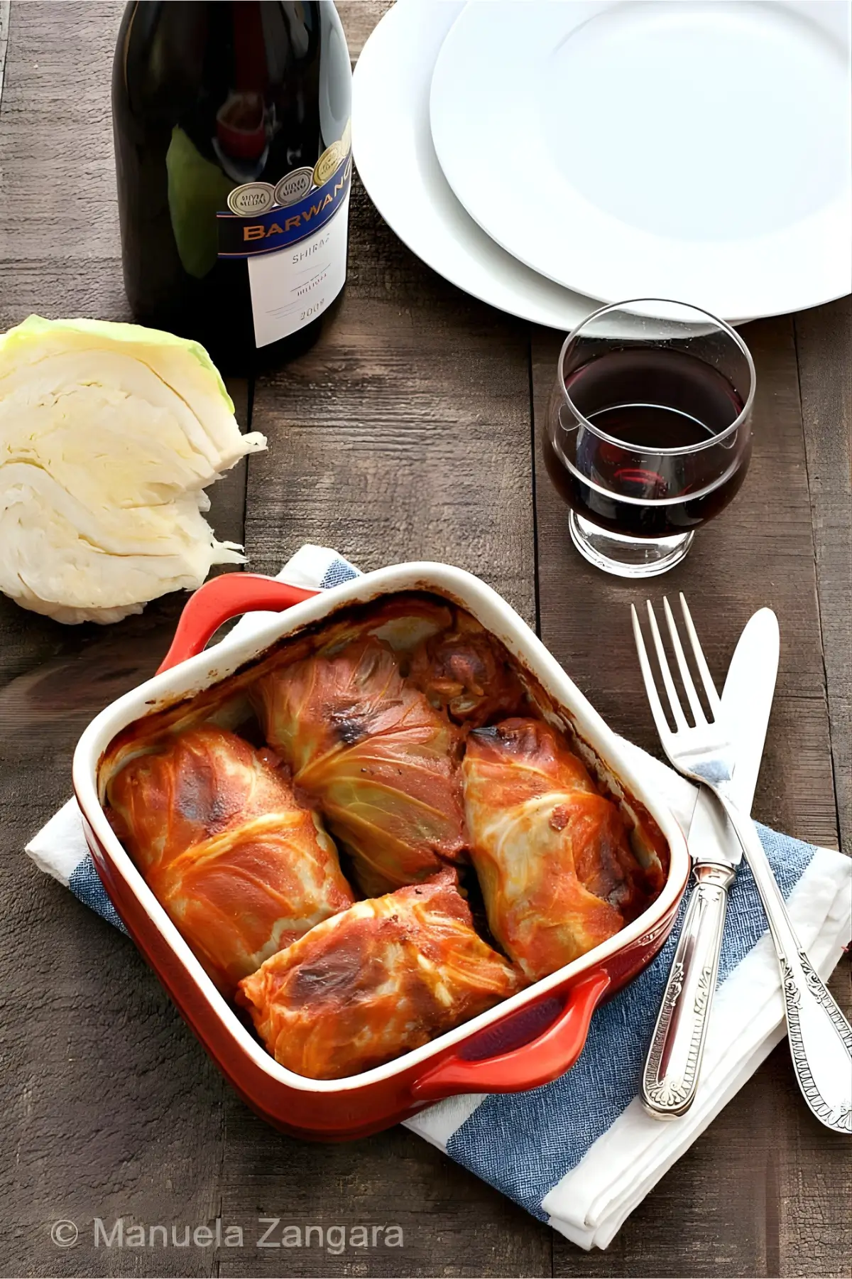 Cabbage rolls baked in tomato sauce with red wine and cut cabbage beside the dish.