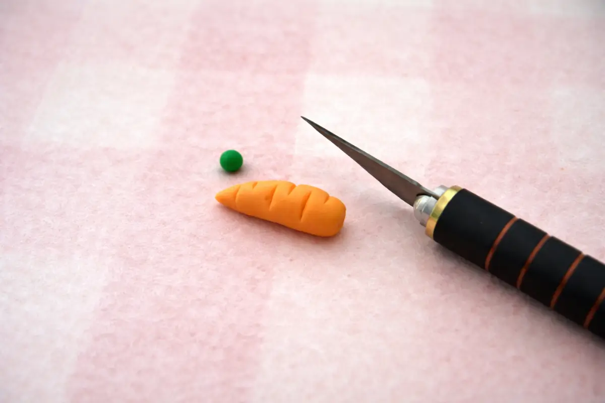Small fondant carrots shaped with a knife and topped with green pieces.