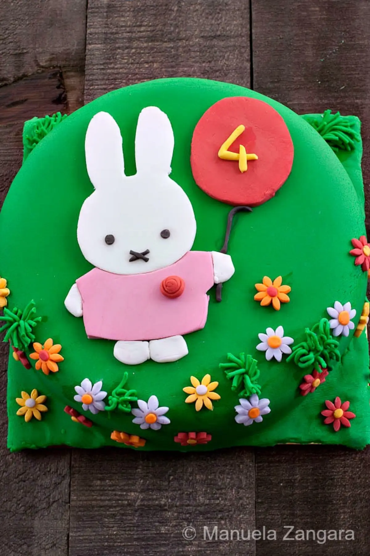 Finished Miffy Cake decorated with green fondant, flat Miffy design, balloon detail, and small fondant flowers.
