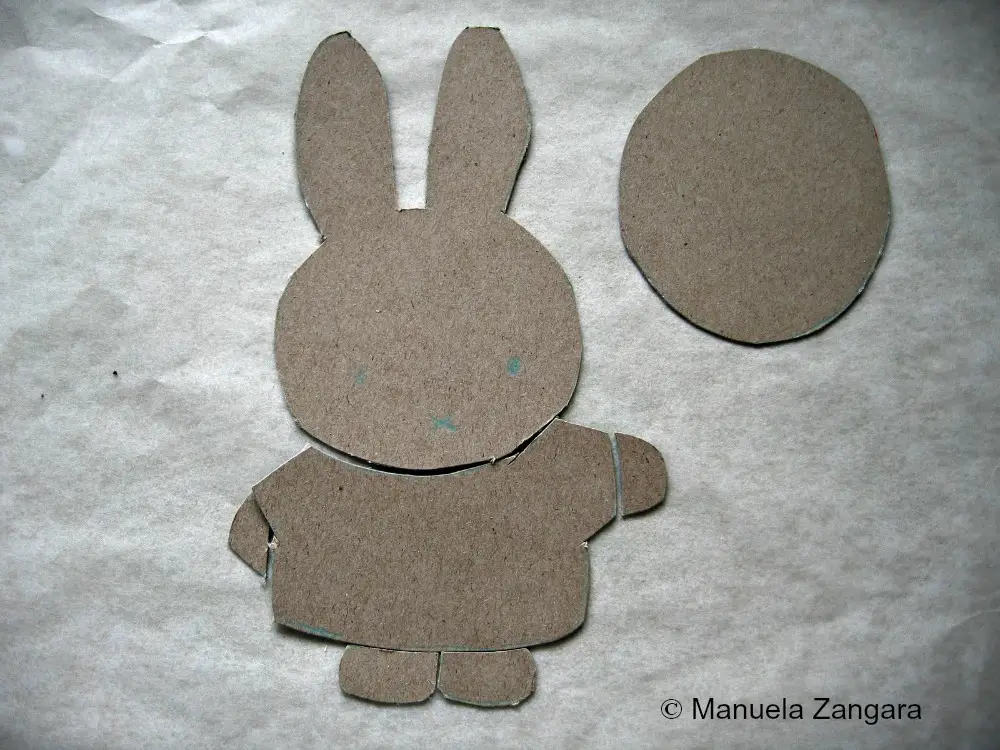 Cardboard stencil pieces cut for creating a flat Miffy fondant decoration.