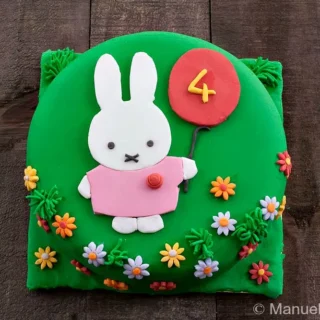 Finished Miffy Cake decorated with green fondant, flat Miffy design, balloon detail, and small fondant flowers.