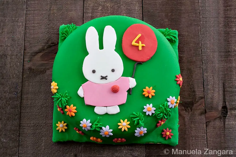 Finished Miffy Cake decorated with green fondant, flat Miffy design, balloon detail, and small fondant flowers.