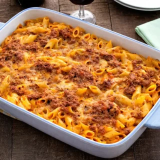 Baked pasta al forno with penne, ragù, and melted cheese on top in a casserole dish.
