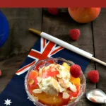 Peach Melba served in a glass bowl with vanilla ice cream, raspberry sauce, and toasted almonds.