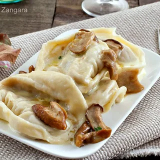 Cappellacci served on a plate with porcini and cream sauce.