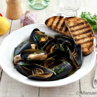 Peppered mussels served with toasted crusty bread and lemon wedges.