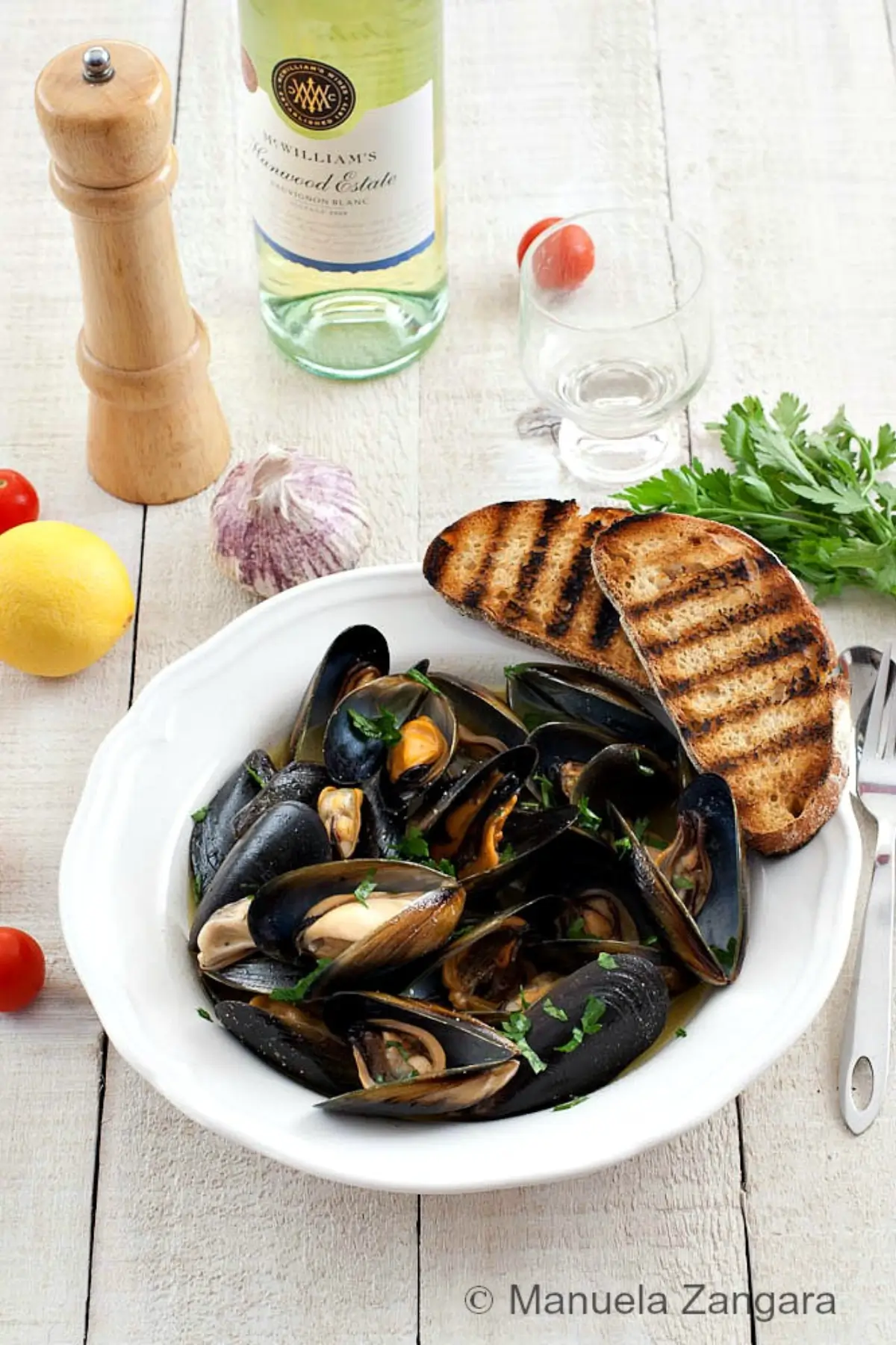 Impepata di Cozze served with toasted bread, lemon wedges, and parsley.