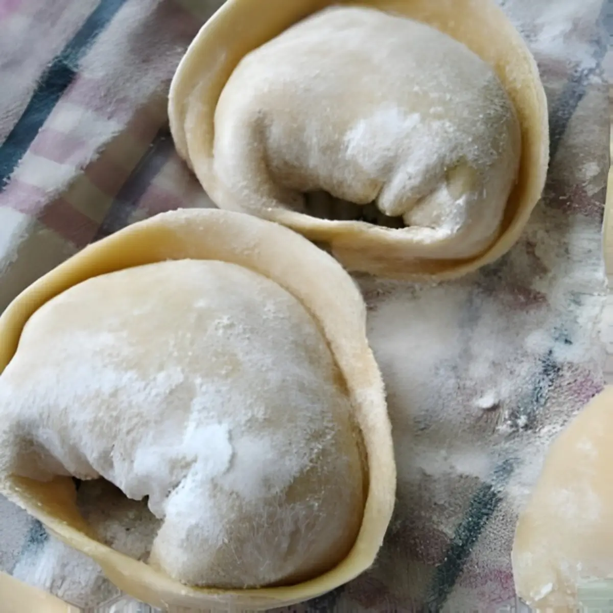 Freshly shaped cappellacci dusted with flour on a cloth.