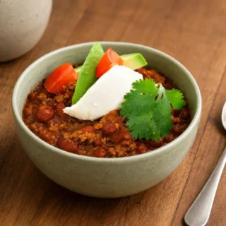 Bowl of beef and bean chilli topped with avocado, tomato, sour cream and fresh coriander.