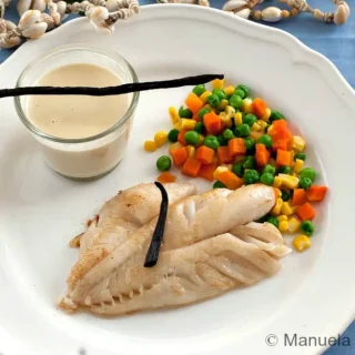 Fish Fillet with Tahitian Vanilla Sauce served with mixed vegetables and a small glass of sauce.