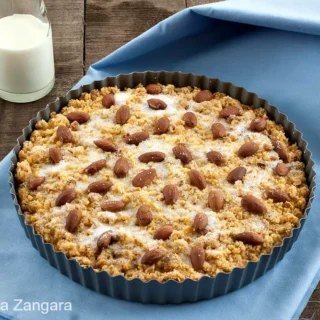 Freshly baked Sbrisolona in a tart pan topped with almonds and sugar.