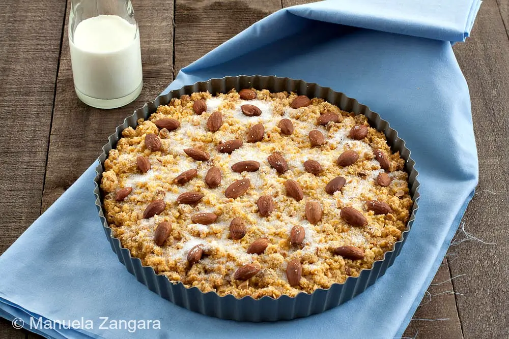 Freshly baked Sbrisolona in a tart pan topped with almonds and sugar.
