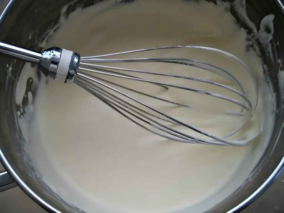 Lightly whipped cream in a bowl with a whisk.