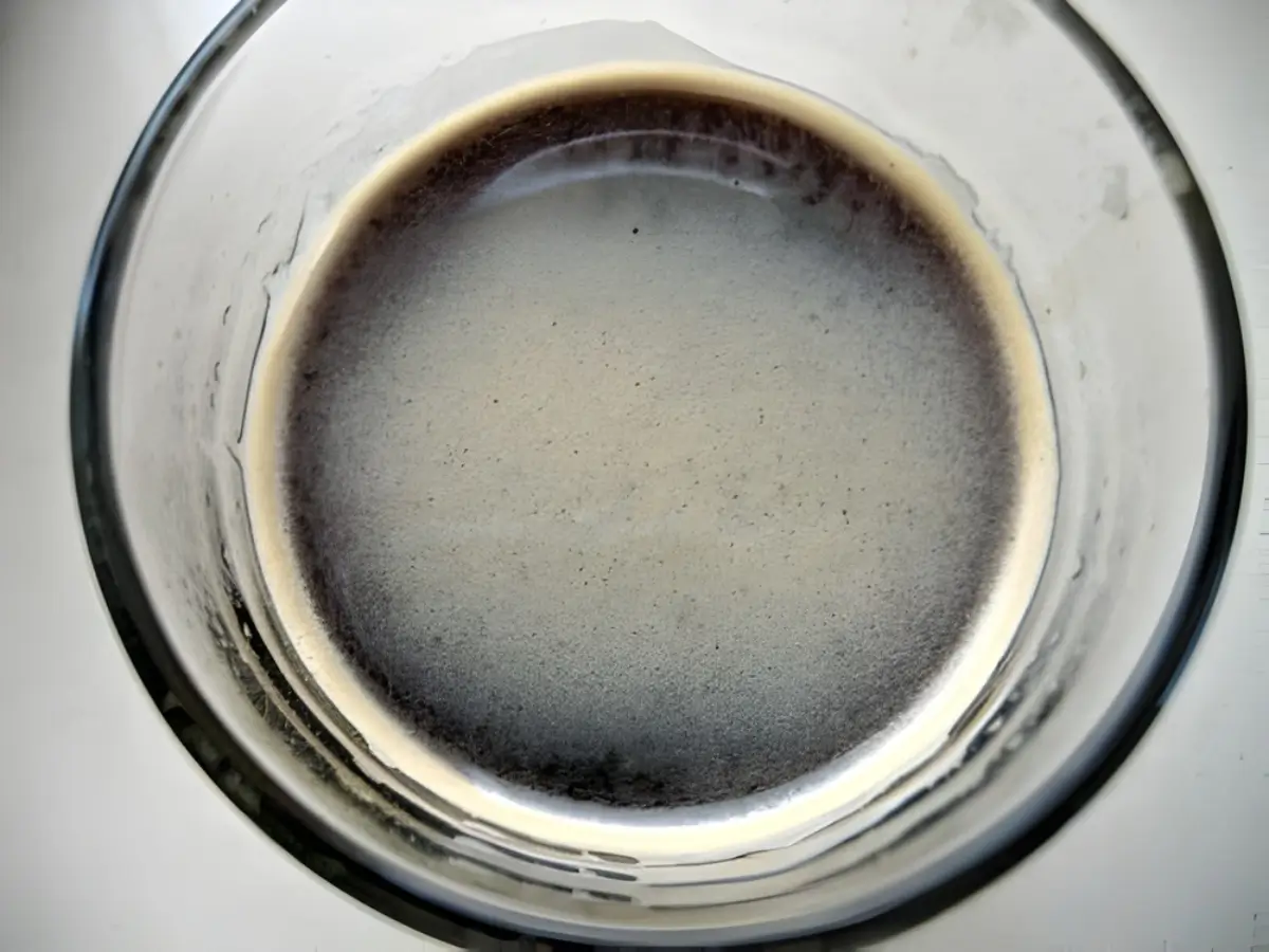 Hot coffee in a clear glass with whiskey mixed in before adding cream.