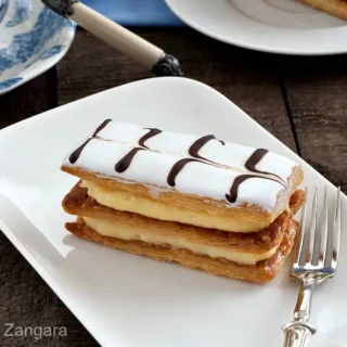 Finished mille-feuille slice on a white plate with a fork.