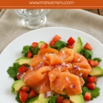 Smoked salmon served with sliced avocado, chopped tomato, cilantro, and red onion on a white plate.