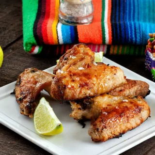 Baked Margarita chicken wings with glaze served with lime and salt.