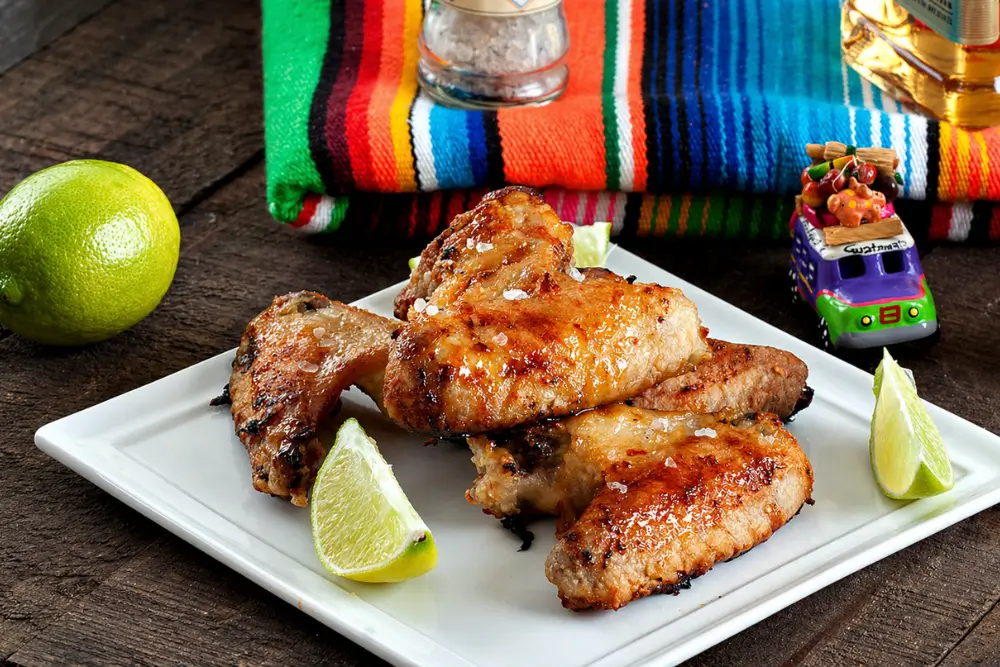 Baked Margarita chicken wings with glaze served with lime and salt.