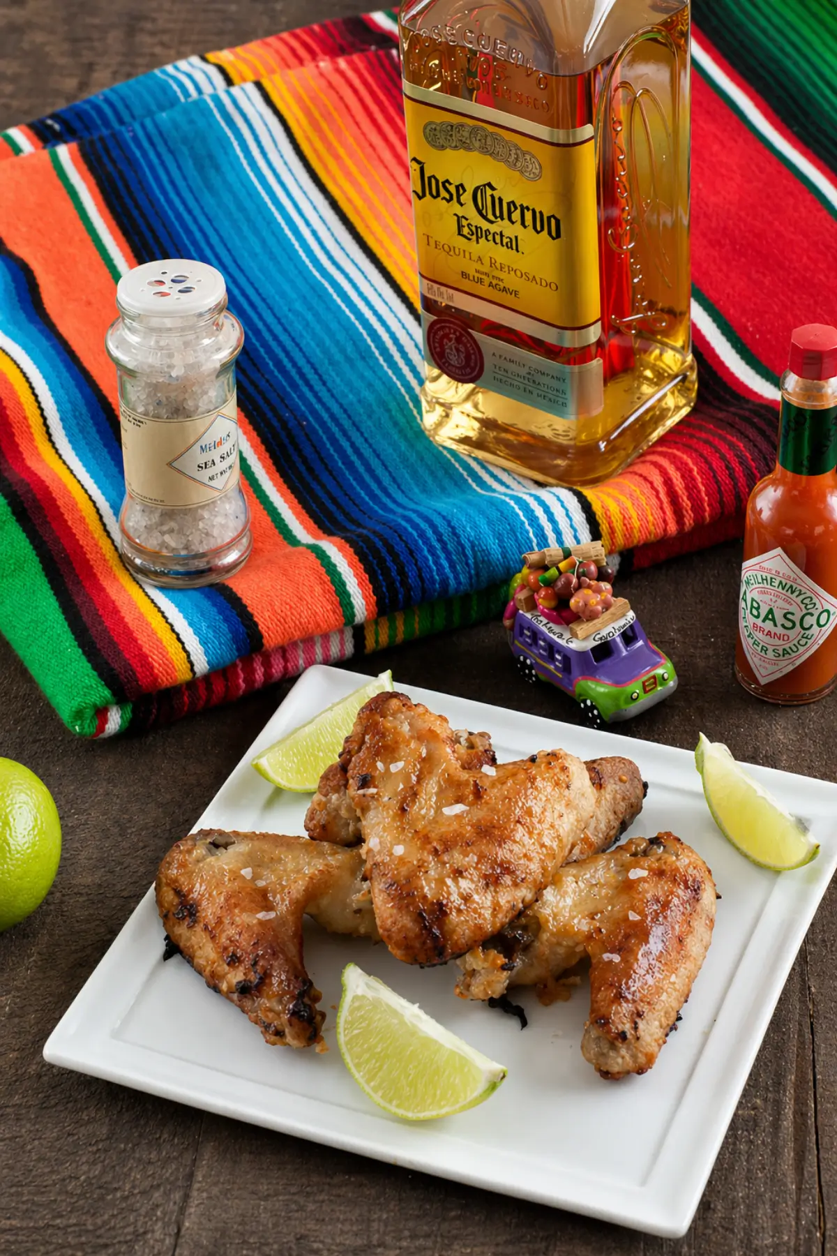 Citrus chicken wings with a glossy coating served with lime wedges on the side.