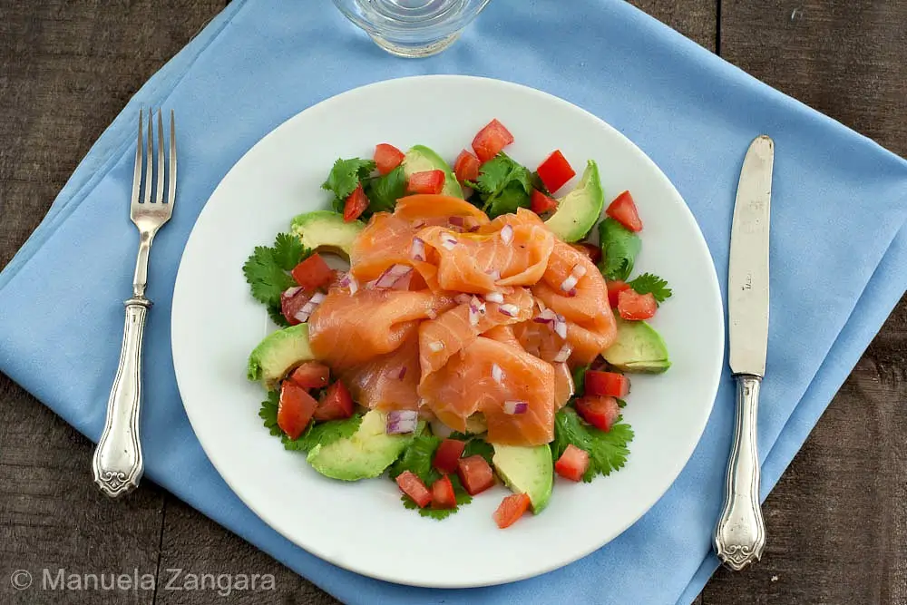 Plated smoked salmon and avocado salad with tomato and coriander.