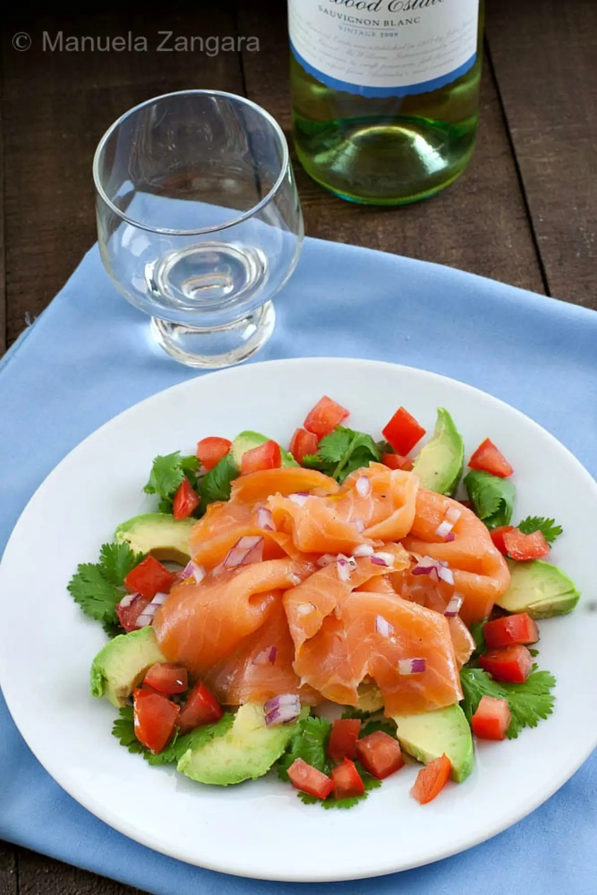 Smoked salmon and avocado salad served with a glass of white wine.