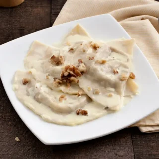 Taleggio Fonduta with Walnut Mezzelune served with creamy cheese sauce and chopped walnuts.