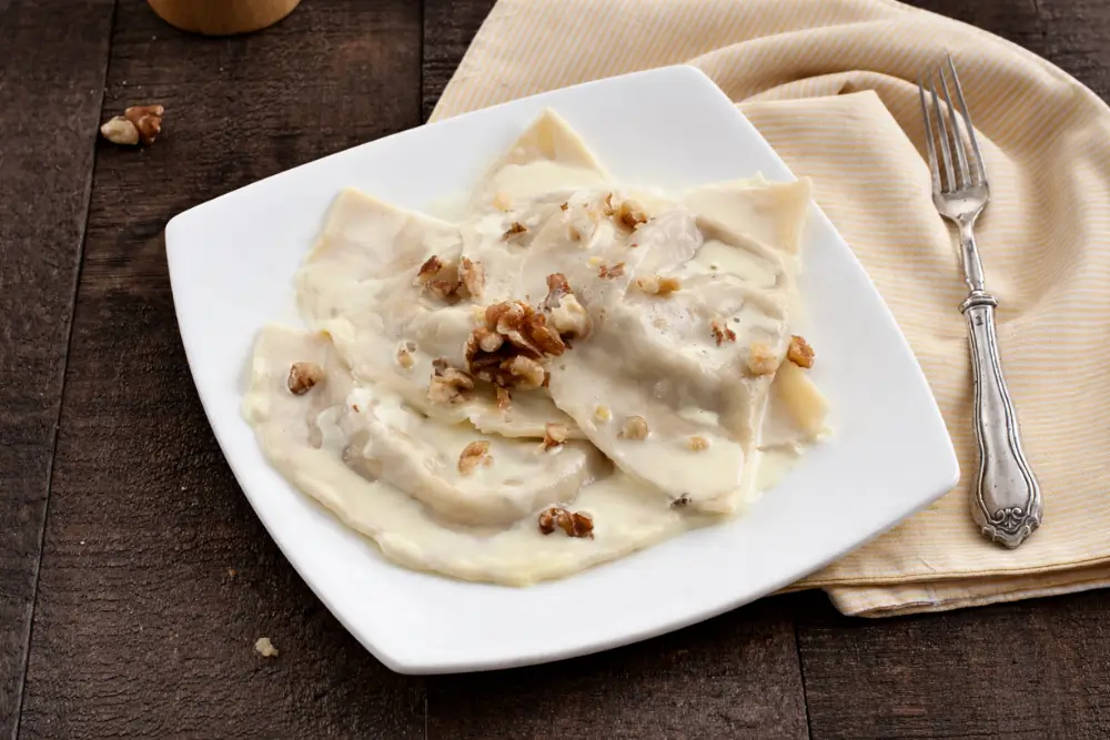 Taleggio Fonduta with Walnut Mezzelune served with creamy cheese sauce and chopped walnuts.
