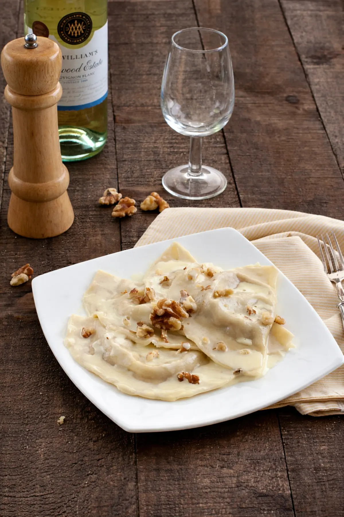 Soft mezzelune coated in creamy cheese sauce on a white plate.