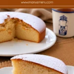 Slice of Eggless Yogurt Cake dusted with icing sugar and served on a white plate beside a cup of tea.