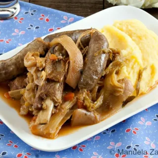 Cassoeula milanese served with creamy polenta on a white plate.