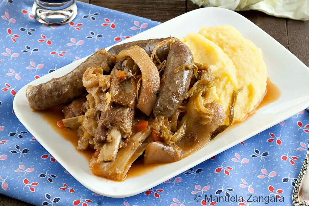 Cassoeula milanese served with creamy polenta on a white plate.