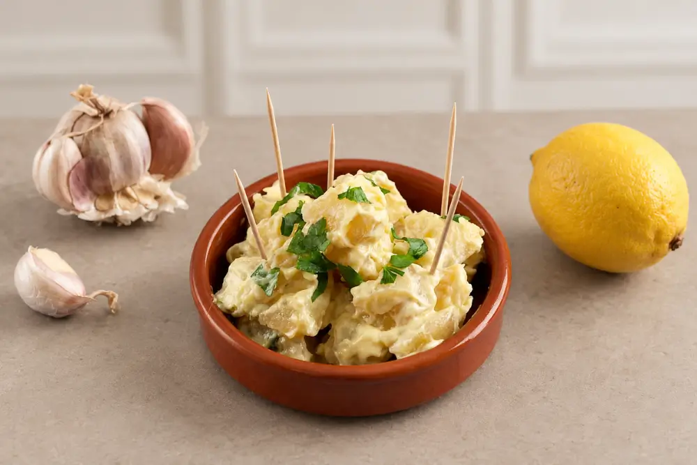 Patatas Aioli topped with chopped parsley and served with toothpicks.