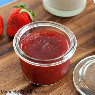 Homemade Strawberry Jam served in a small glass jar with fresh bread.