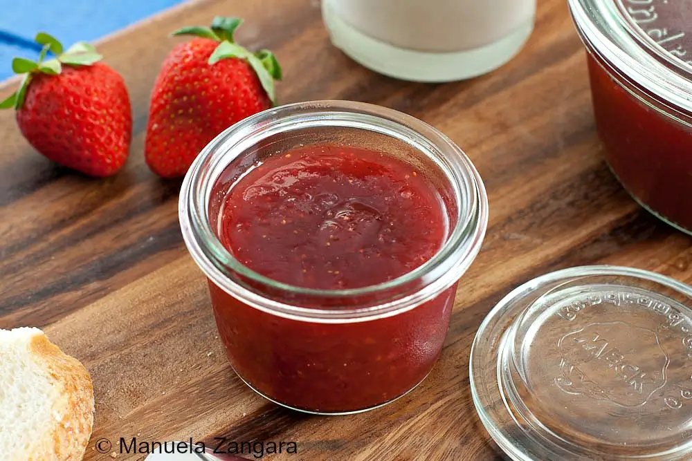 Homemade Strawberry Jam served in a small glass jar with fresh bread.