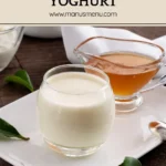 Panna cotta in a glass served with honey in a small jug on a white plate.