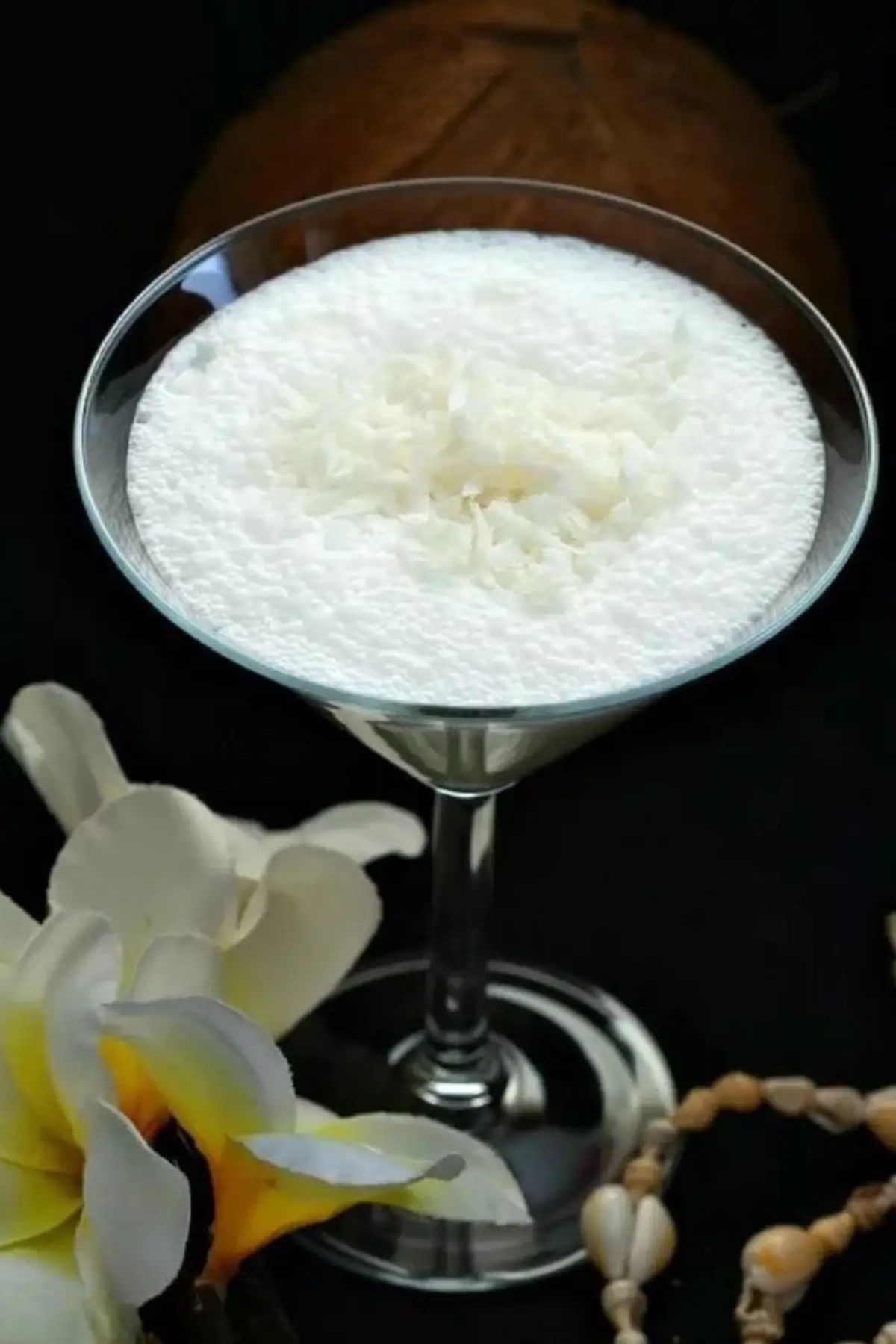 Batida de Coco cocktail topped with shredded coconut in a martini glass.