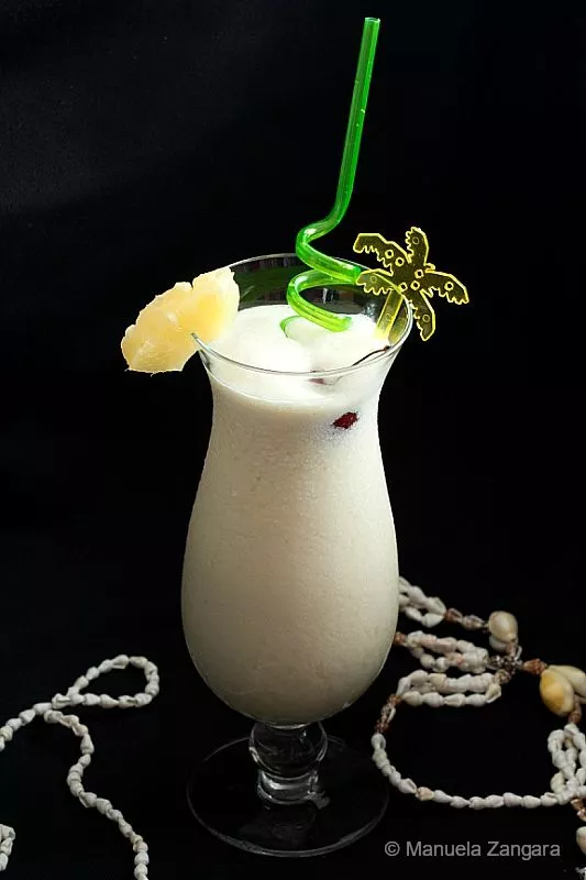Frozen Piña Colada garnished with pineapple slice and green straw.Enjoy its chilled, creamy texture and refreshing flavour.