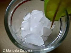 Glass filled halfway with ice cubes and lime slice on rim.