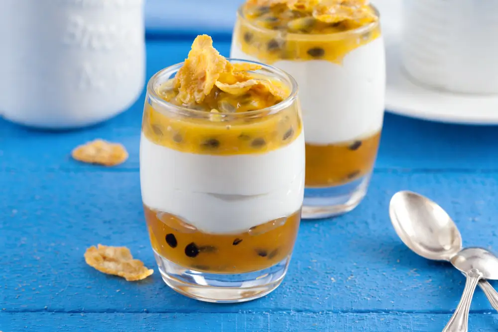 Tropical verrine with yoghurt, passion fruit and cornflakes served in a small glass.