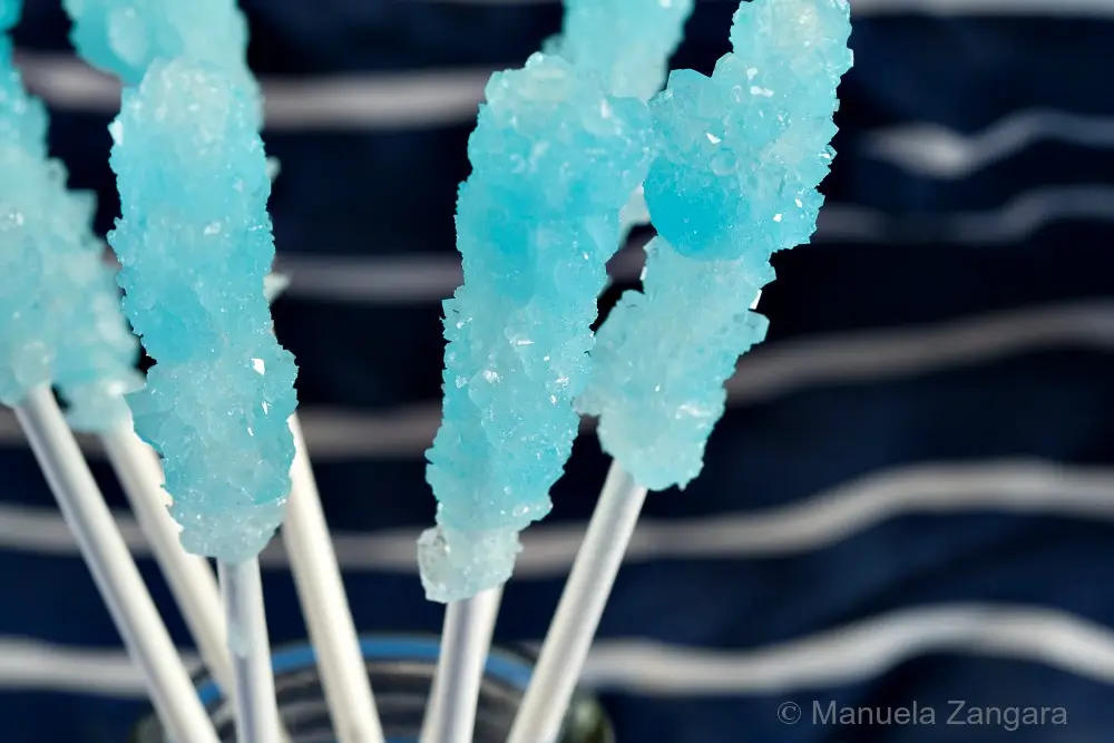 Close-up of a blue rock candy lollipop forming crystals on the stick.