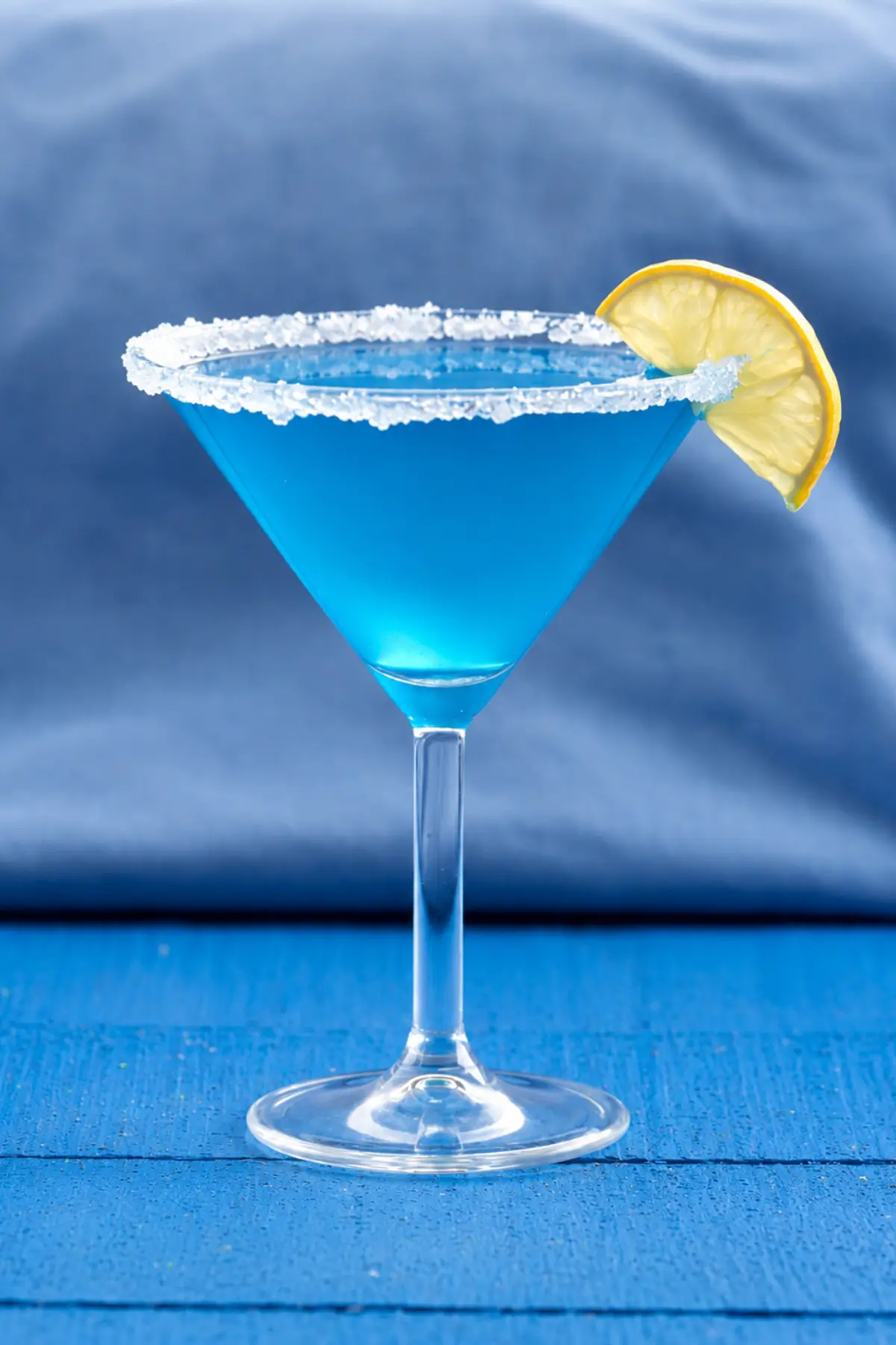 Chilled blue curaçao cocktail with a sugared rim and fresh lemon wedge.