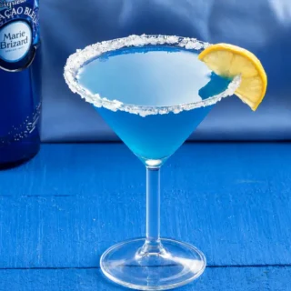 Blue Daiquiri cocktail beside a bottle of Blue Curaçao liqueur.